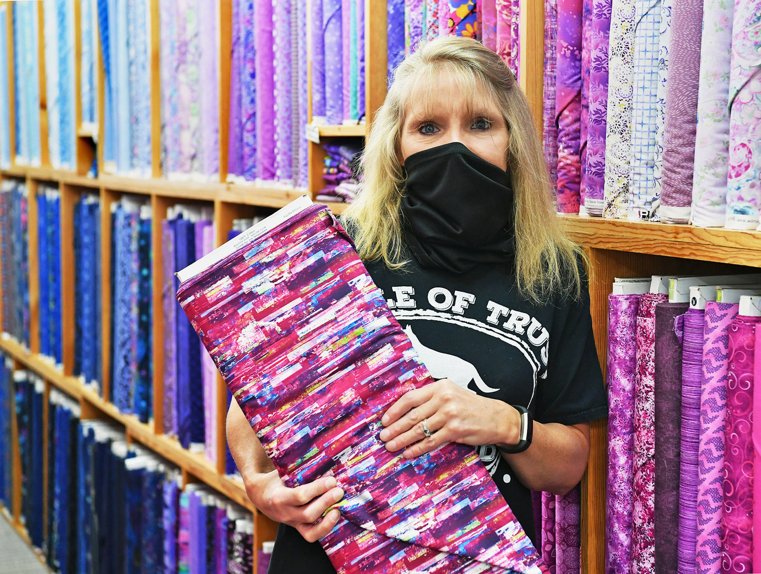 Candi Sullivan, 51, has managed Gee-Gee's Quilting Inc. for the past 25 years. Here she displays a bolt of colorful cloth in the store on Friday, July 17.