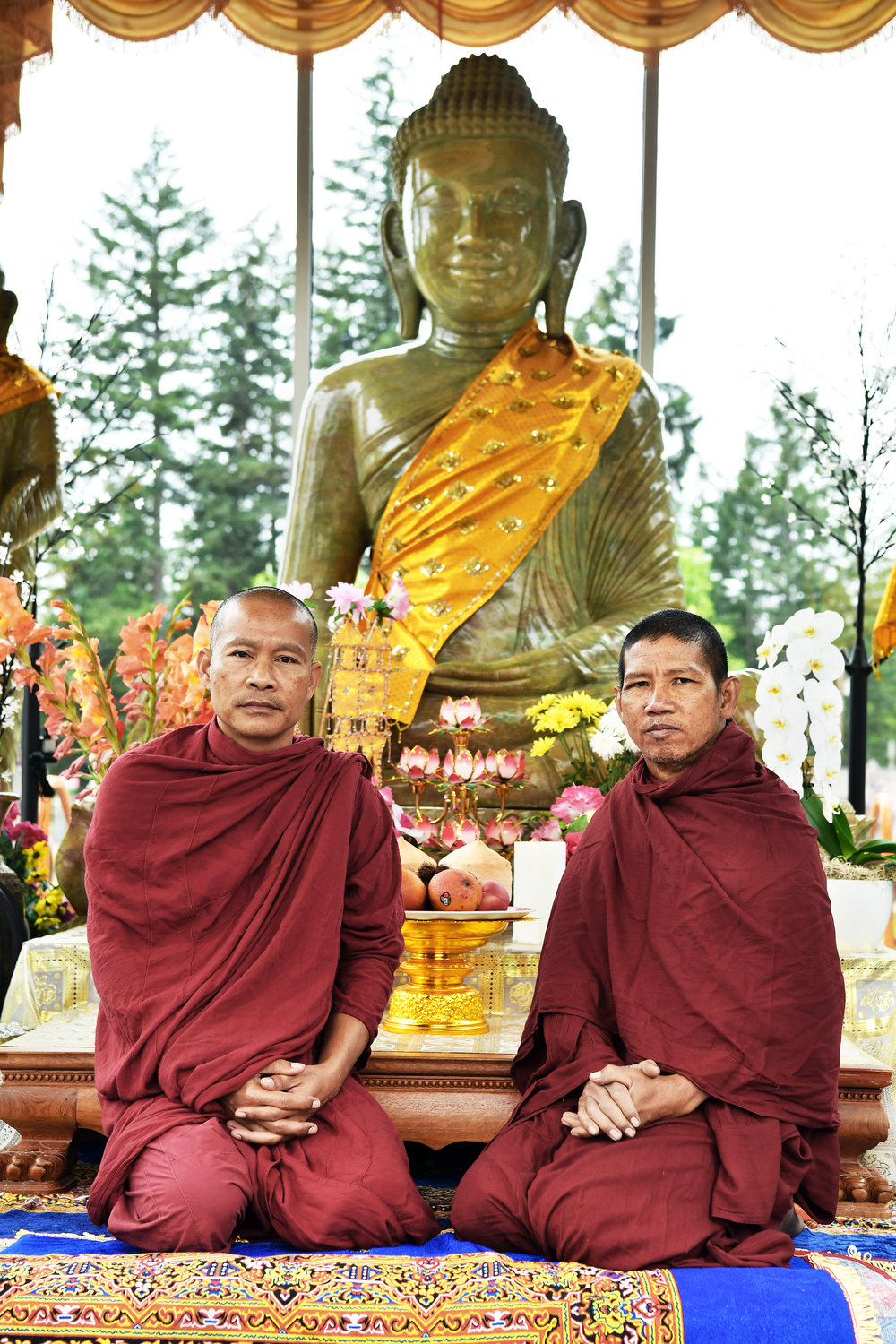 Buddhist monks Kosal Suon, 50, left, and Bunthon Sok, 50, kneel on Friday, July 24, at the entrance to the "Stupa," the main Buddha's house on the grounds of the Wat Prachum Raingsey Buddhist Association in Yelm.