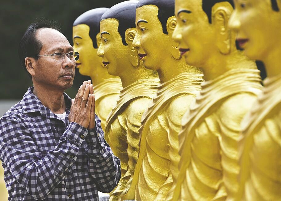 Chheth Chuon, 61, current president of the Wat Prachum Raingsey Buddhist Association in Yelm, prays on Friday, July 24 before statues representing the first students of the Buddha.