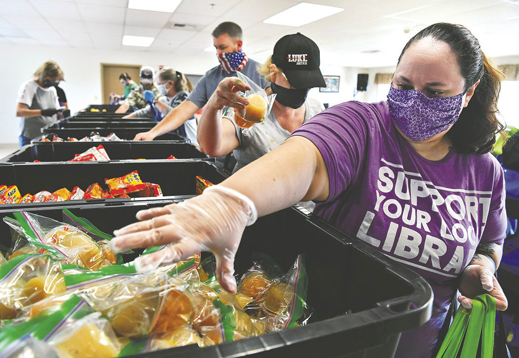 Yelm resident Erica McCaleb, 30, grabs containers of fruit cups to add to her bag on Sunday, July 12, at the Yelm Senior Center. McCaLeb was among a group of Rotary Club of Yelm members and volunteers loading food bags for the club's "10 Weeks of Summer Lunch Program."