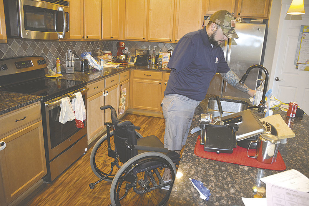 Aaron Boyle stands to use the sink, but his wheelchair blocks others for using the rest of the kitchen in his current house.