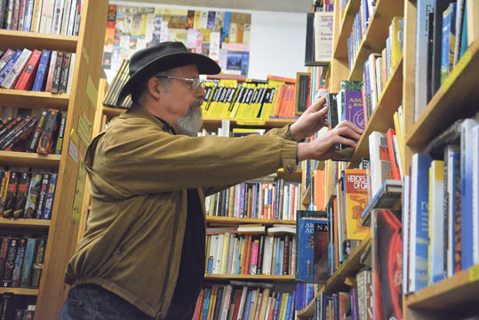 Bob Maddox, owner of A Novel Bookstore, reshelves a few editions to get the shelf looking just right.