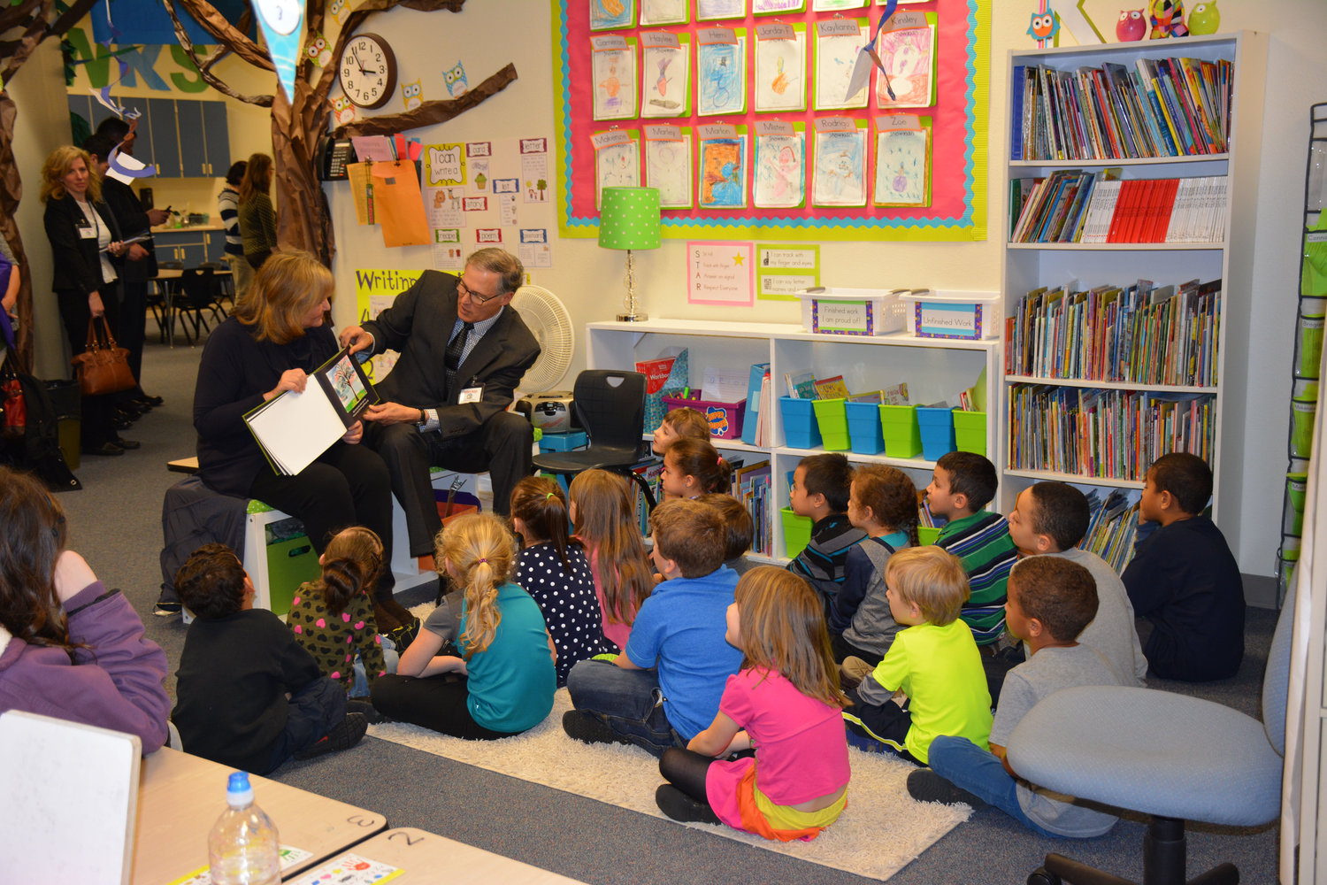 Gov. Jay Inslee, seated on bench, reads a children's book he wrote to a group of young students at Fort Stevens Elementary School in Yelm Thursday, Feb. 5 with the help of his wife, Trudi. The governor visted Fort Stevens and Yelm High School to learn about their successful early learning and career and technical education programs he would like to make available statewide.