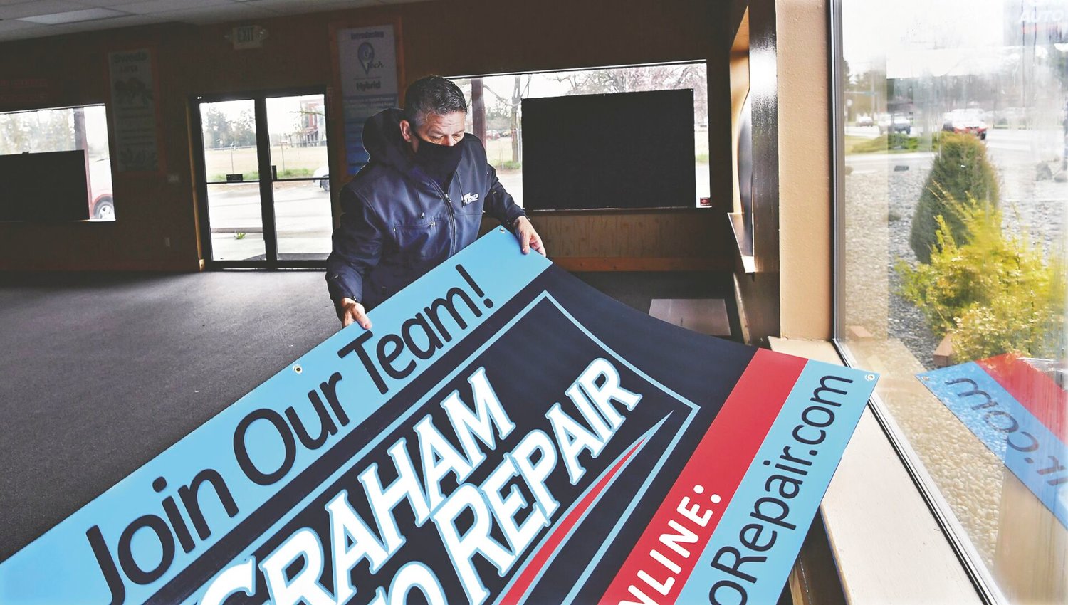Troy Vaninetti, 49, who with his wife Kori, 47, owns Graham Auto Repair in Graham and the soon-to-open Graham Auto Repair in Yelm, replaces an employee recruiting poster in a window of the new facility on Yelm Avenue East on Thursday, March 25.