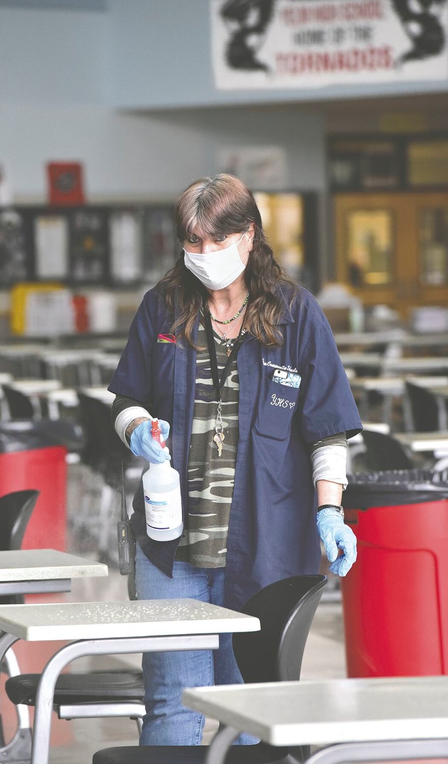 Yelm High School head custodian Janice Giffin, 59, demonstrates how she disinfects and sanitizes tables on Monday, March 8, in the YHS commons where students will eat when they return to school on March 15.