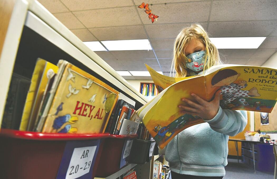 Prairie Elementary School second-grade student Emilie Alexander browses a book on Tuesday, Feb. 16 from the classroom's reading library.