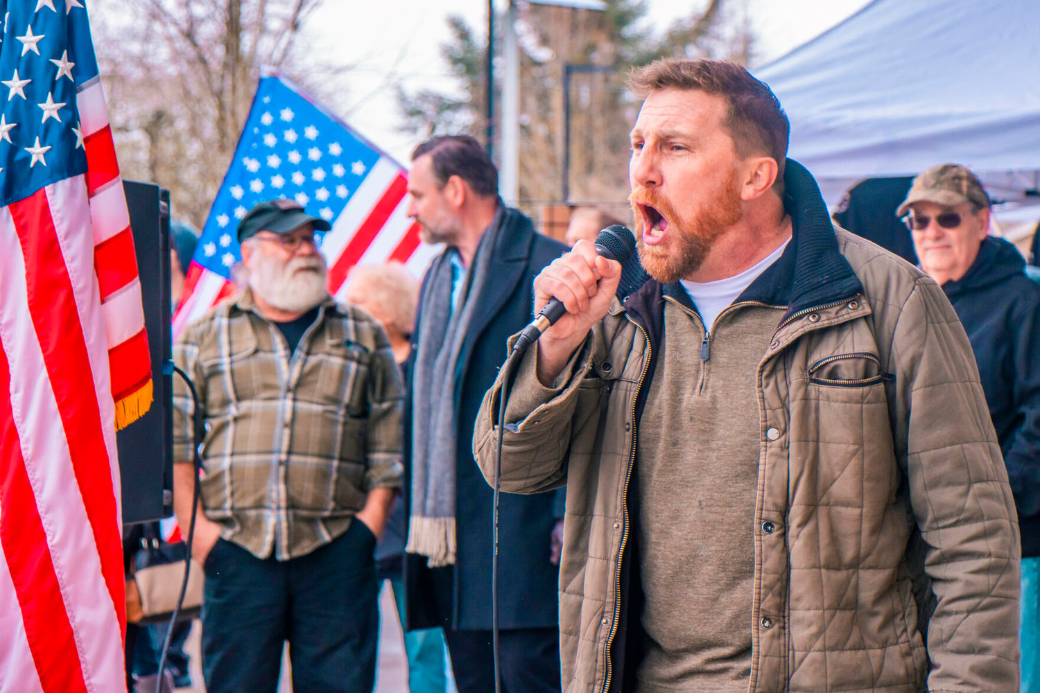 Erik Rohde, of the Washington Three Percenters, yells to crowds through a mic during a protest to ‘Open Yelm Now’ at Yelm City Park on Saturday.