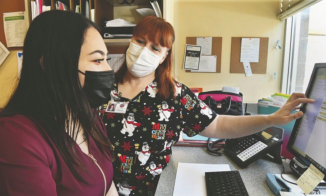 Stephanie Tucksen, 42, Yelm Family Medicine clincal supervisor and certified medical assistant, right, reviews electronic health records at the clinic on Thursday, Dec. 24, with Vanessa Fields, 21, a certified medical assistant.