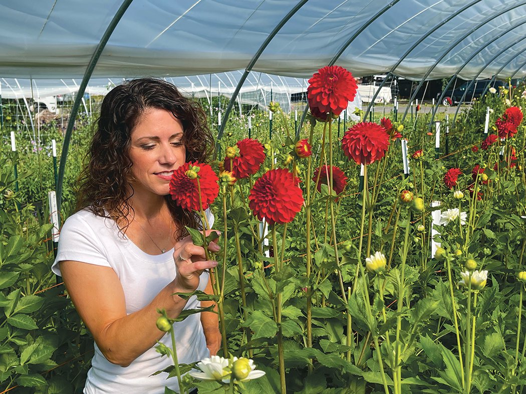 Tabatha Sand, owner of Braids and Blossoms Flower Farm, smells a dahlia in one of her hoop houses, located at 396 Sussex Ave. E. in Tenino.
