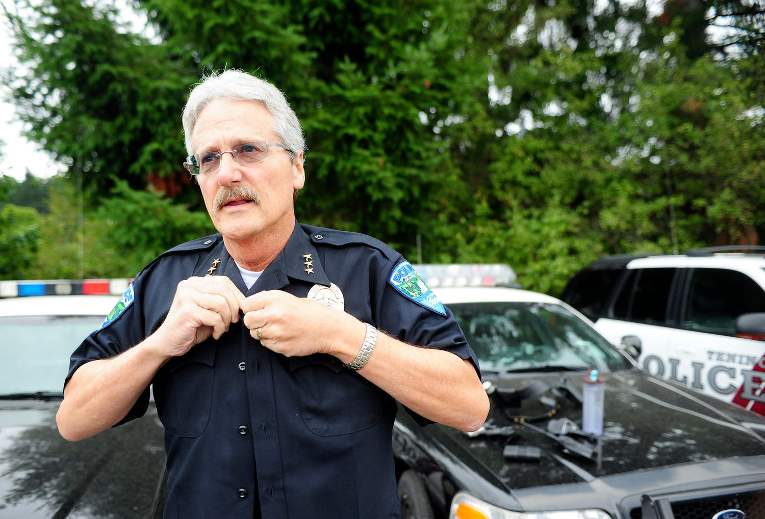 FILE PHOTO — Interim Tenino Police Chief John Hutchings buttons up his shirt after putting on a bulletproof vest prior to heading out on the road.
