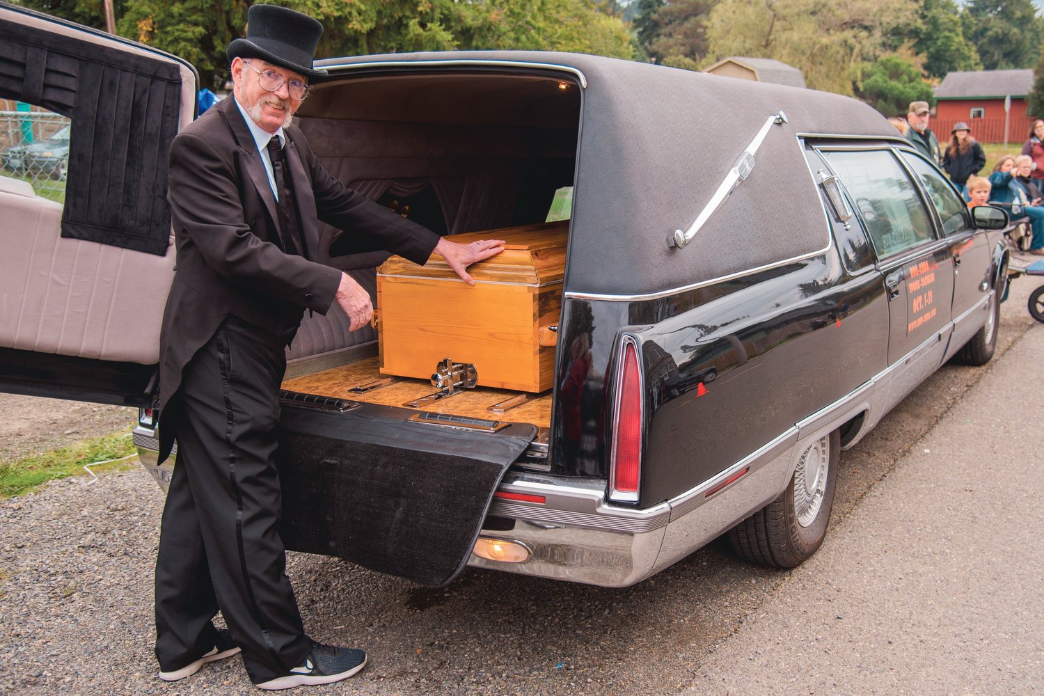 Steve Purcell smiles as he opens the back of “Hearsela,” a Cadillac hearse, to reveal a casket before the Casket Races outside Bucoda Town Hall Saturday afternoon.