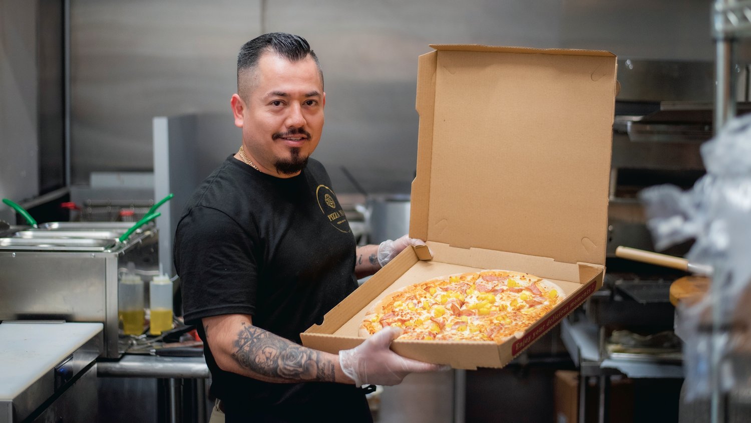 Jose Villegas smiles and holds up a box ready to be served at Pizza Mia in Tenino.