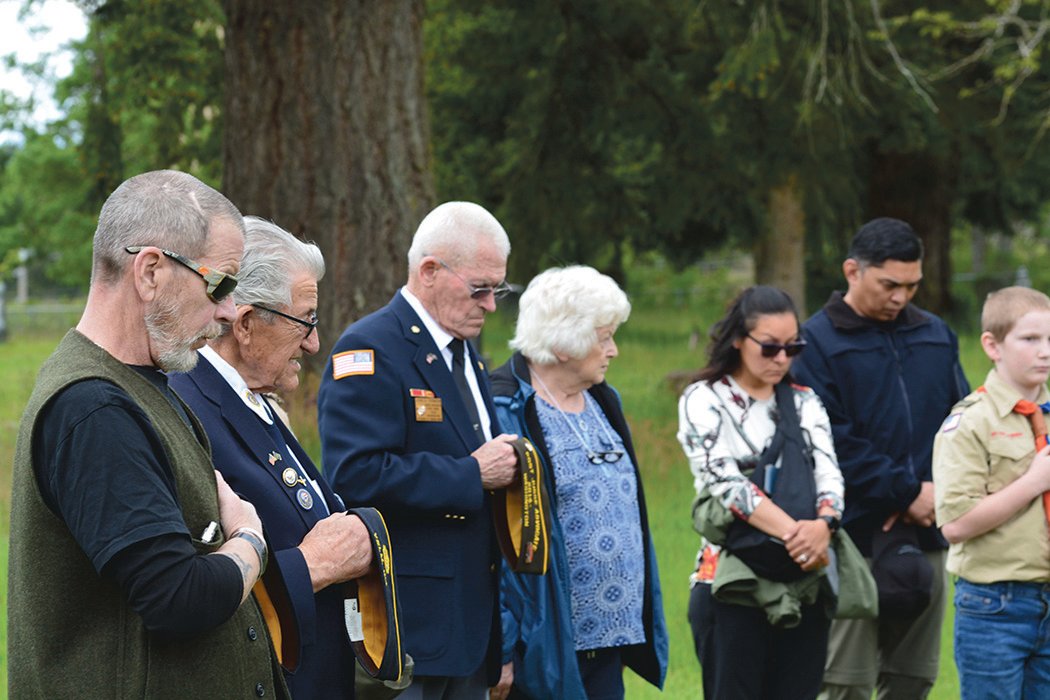 Veterans at a Memorial Day event in Roy remove their hats and bow their heads during a moment of remembrance.