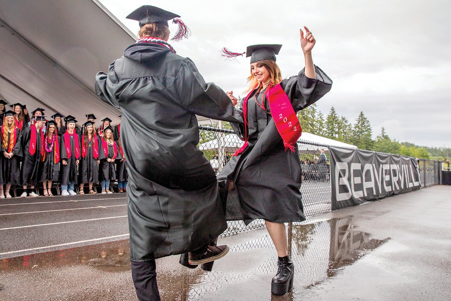 Graduates smile and lock hands as they touch feet and spin during a ceremony at Beaver Stadium on Friday.