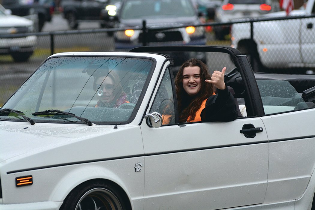 A Rainier High School graduate shows off a “hang loose” sign during a parade on June 10.