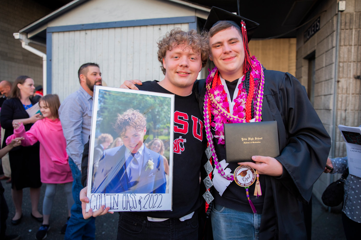 A graduate stands with a photo in memorial of Collin McLaren, who died during his senior year of high school.