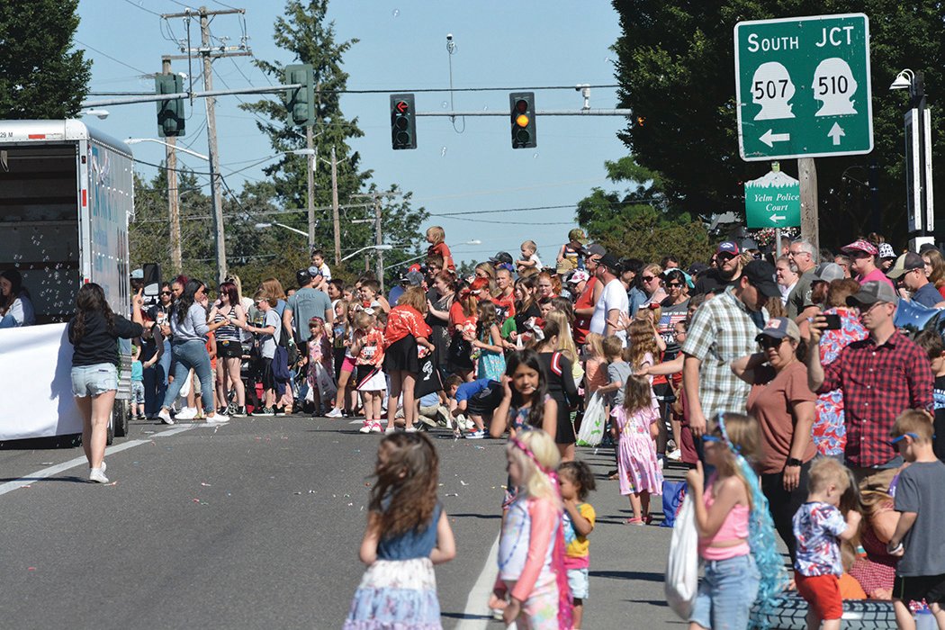 A crowd of parade attendees gather near the light at the intersection of Yelm Avenue and state Route 507 on Saturday, June 25.