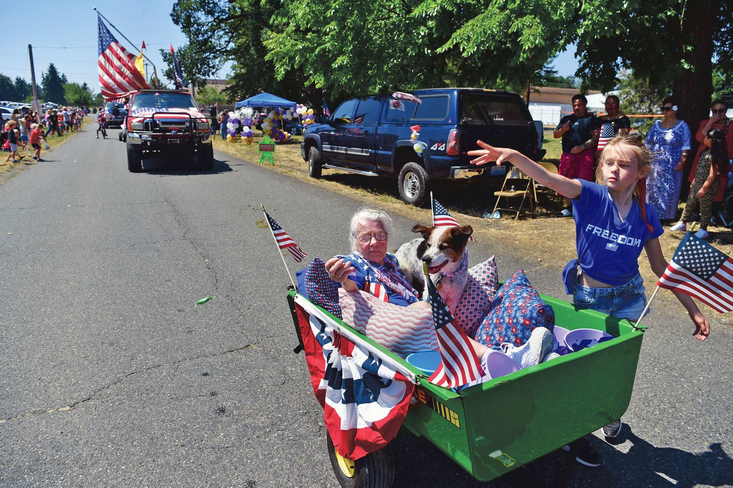 With her passengers tucked safely away in a cocoon of pillows, a girl heaves a handful of candy to waiting spectators at a previous Fourth of July parade in Roy.