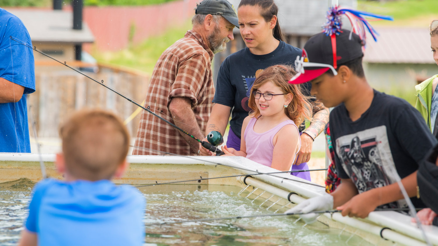 Kids use poles to fish for rainbow trout in a tank from the Aberdeen Hatchery at the Lions Den Campground in Mineral on Saturday.