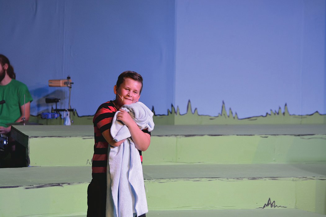 An actor portraying Linus Van Pelt gives his best friend, his blanket, a hug.