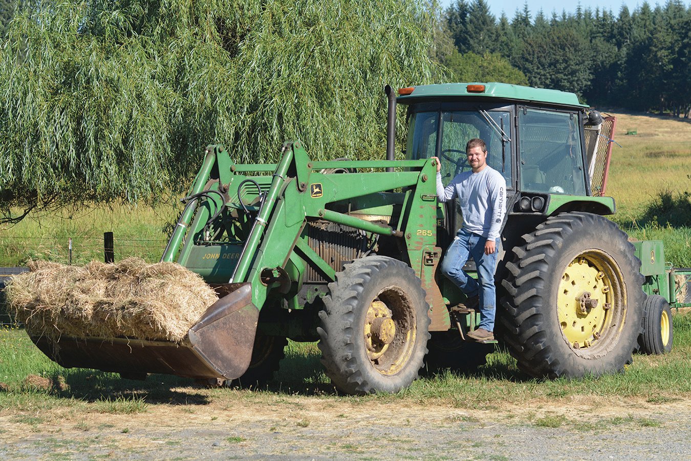 Colton Lester poses for a photo with the always reliable John Deere tractor after hay season condluded.
