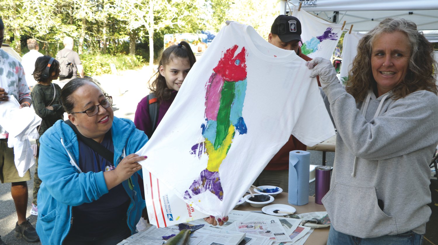 Attendees of the Nisqually Watershed Festival hold up a custom salmon-themed shirt on Saturday, Sept. 24.