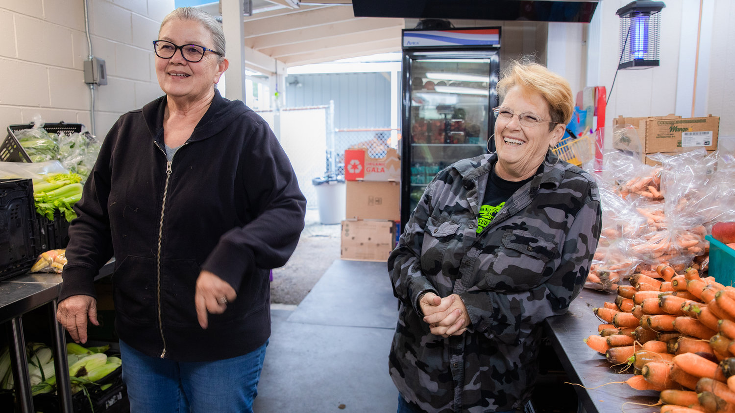 Volunteers smile while talking about a new heater installed to make food prep outside the Tenino Food Bank Plus a warmer experience.