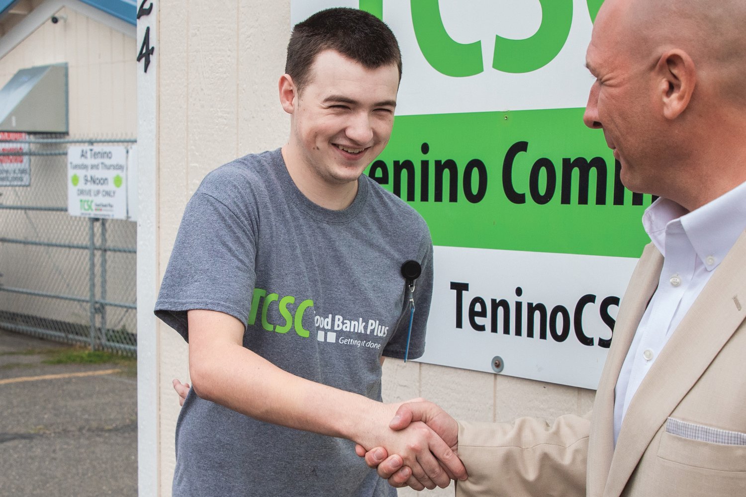 State Rep. Peter Abbarno, right, shakes the hand of Korbin Pearson, 21, a Tenino graduate with special needs who works at the location three days a week as part of a newly established program at Tenino Food Bank Plus.