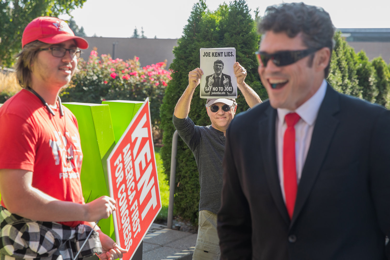 Joe Kent smiles alongside supporters and protesters outside the Vancouver Community Library Saturday afternoon ahead of the Congressional 3rd District Debate.