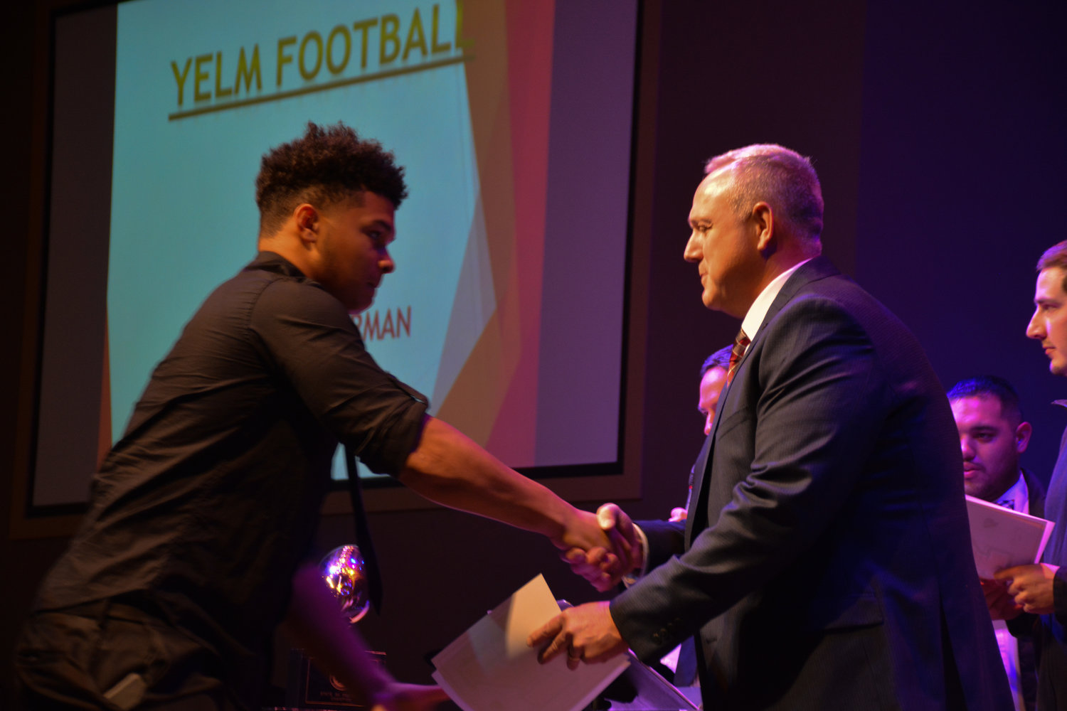 Junior linebacker shakes hands with Coach Brian Foote and accepts his varsity letter for the 2022-2023 season.