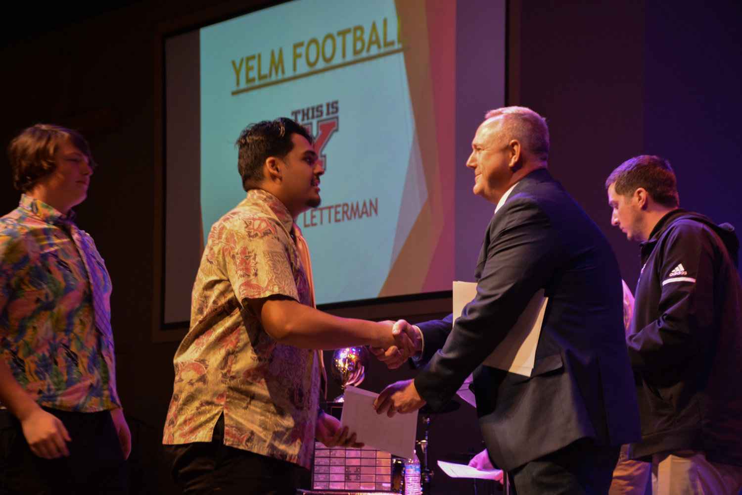 Junior offensive lineman Kyle Kaaiwela accepts his varsity letter from his position coach Brian Foote, while lineman Tyler Blevins waits to accept his.