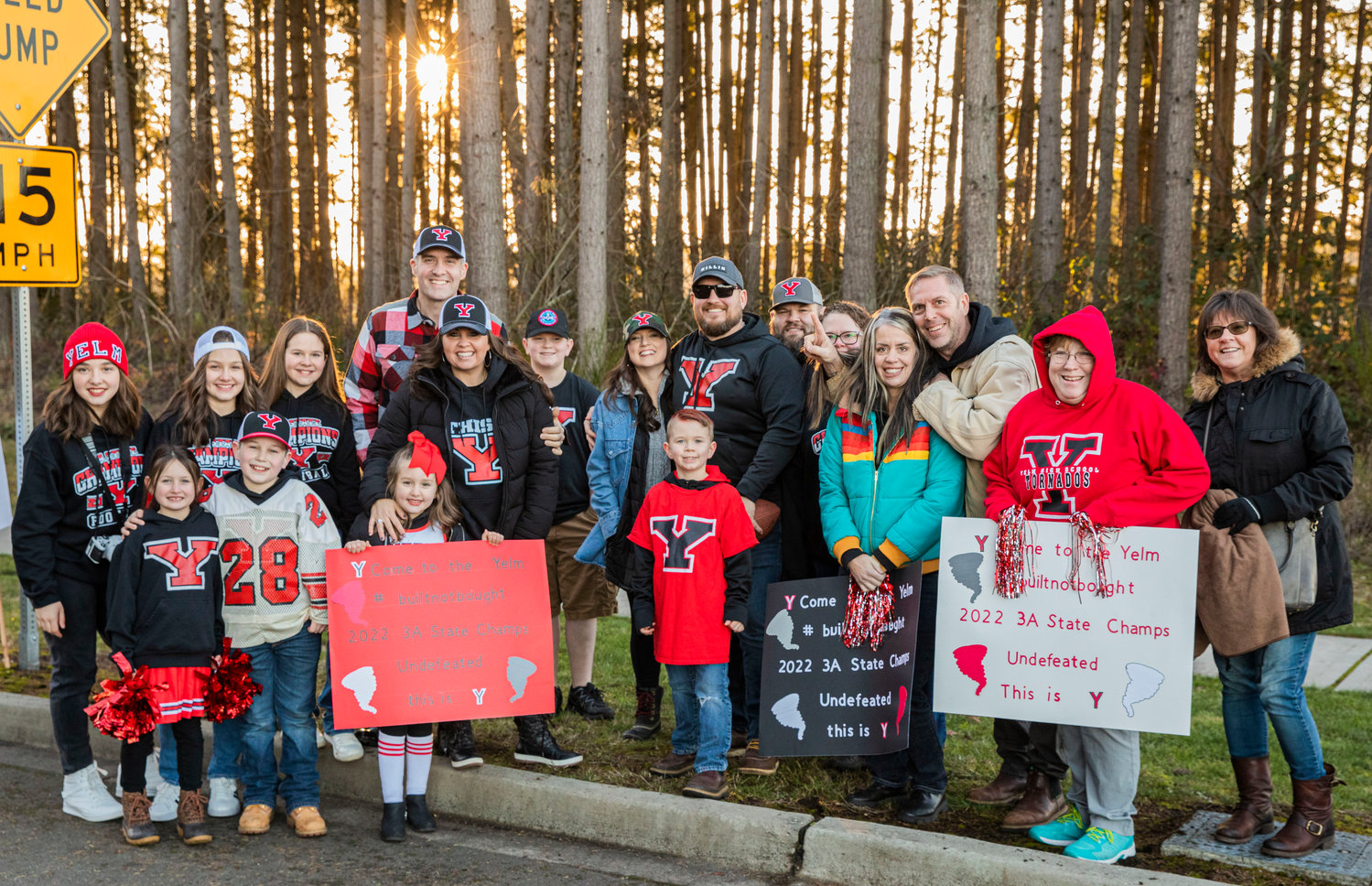 Tornado football fans smile for a photo while holding signs for a celebration parade in Yelm Monday evening.