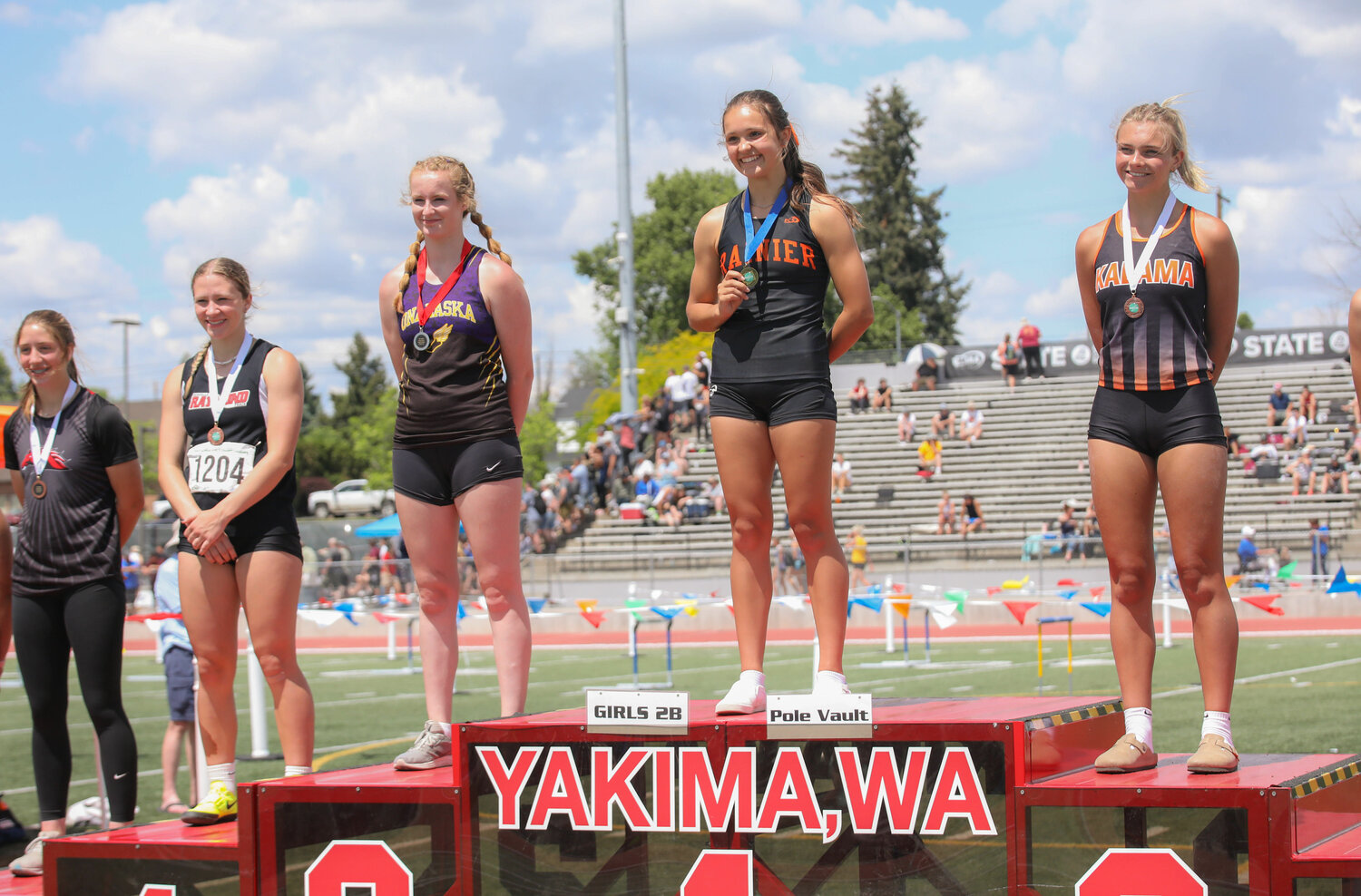 Rainier's Ella Marvin (center) and Onalaska's Kelsi Haas (third from left) stand on the podium after wrapping up the top two places in the girls pole vault at the 2B state track and field championships, May 26 in Yakima.