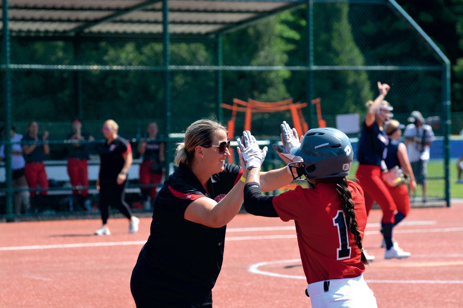 Coach Lindsay Walton high-fives Madisyn Erickson after she drove in runner Elissa Dewees for an RBI on May 25 in Lacey.