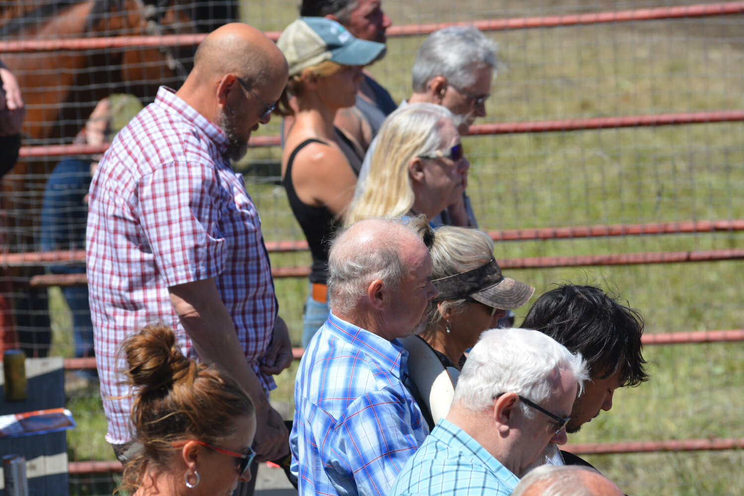 Roy Pioneer Rodeo attendees bow their heads as a prayer is read over the speakers on June 4.