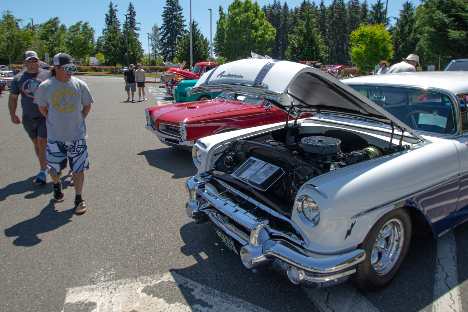 Car show attendees look at Thomas Kelly's restored 1956 Pontiac Safari wagon on Sunday, June 4, at the Yelm High School car show.