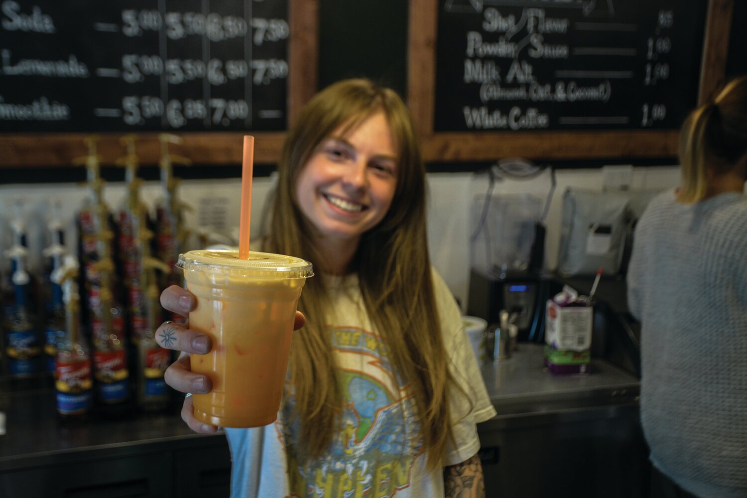 Presly Littlejohn, an employee at Worthy Coffee Co., holds out a drink at the business on June 26.