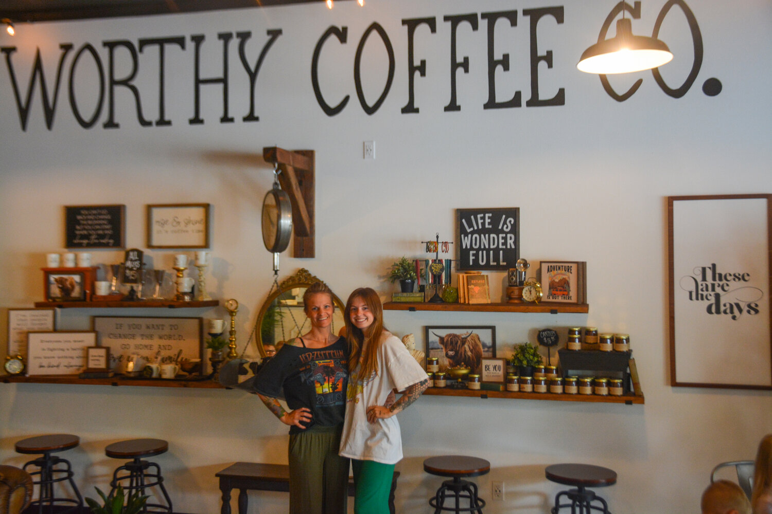 Brandi Worthy and Presly Littlejohn smile near a decorative wall at Worthy Coffee Co. in McKenna on June 26.