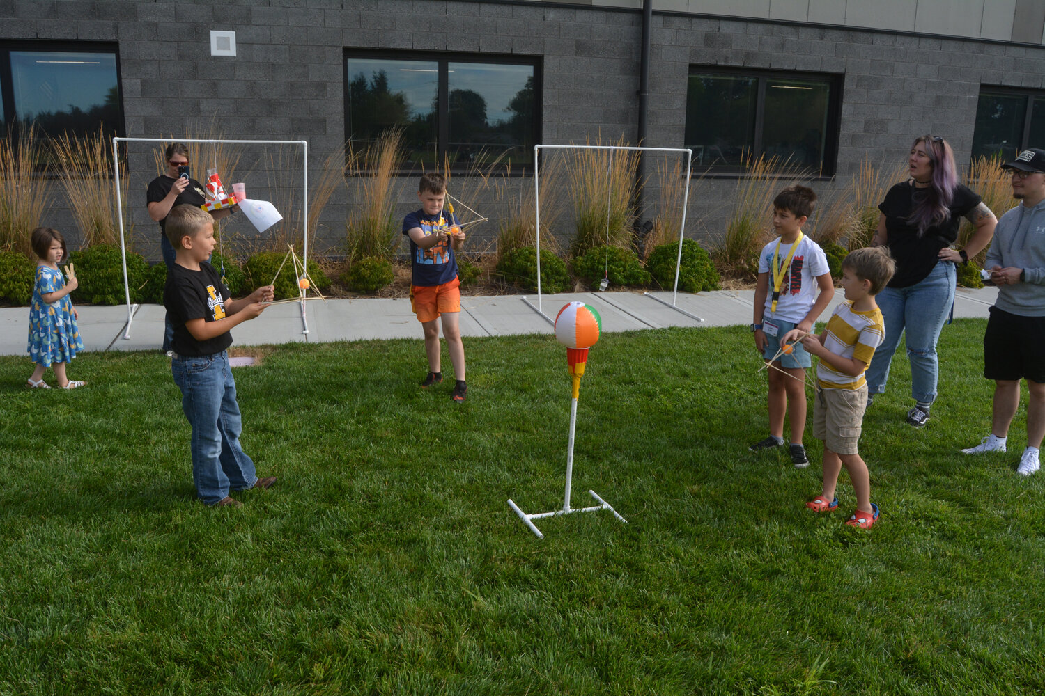 Students gather around a beach ball, slinging ping pong balls to imitate the redirection of asteroids at STEMKAMP Family Day on Aug. 11.