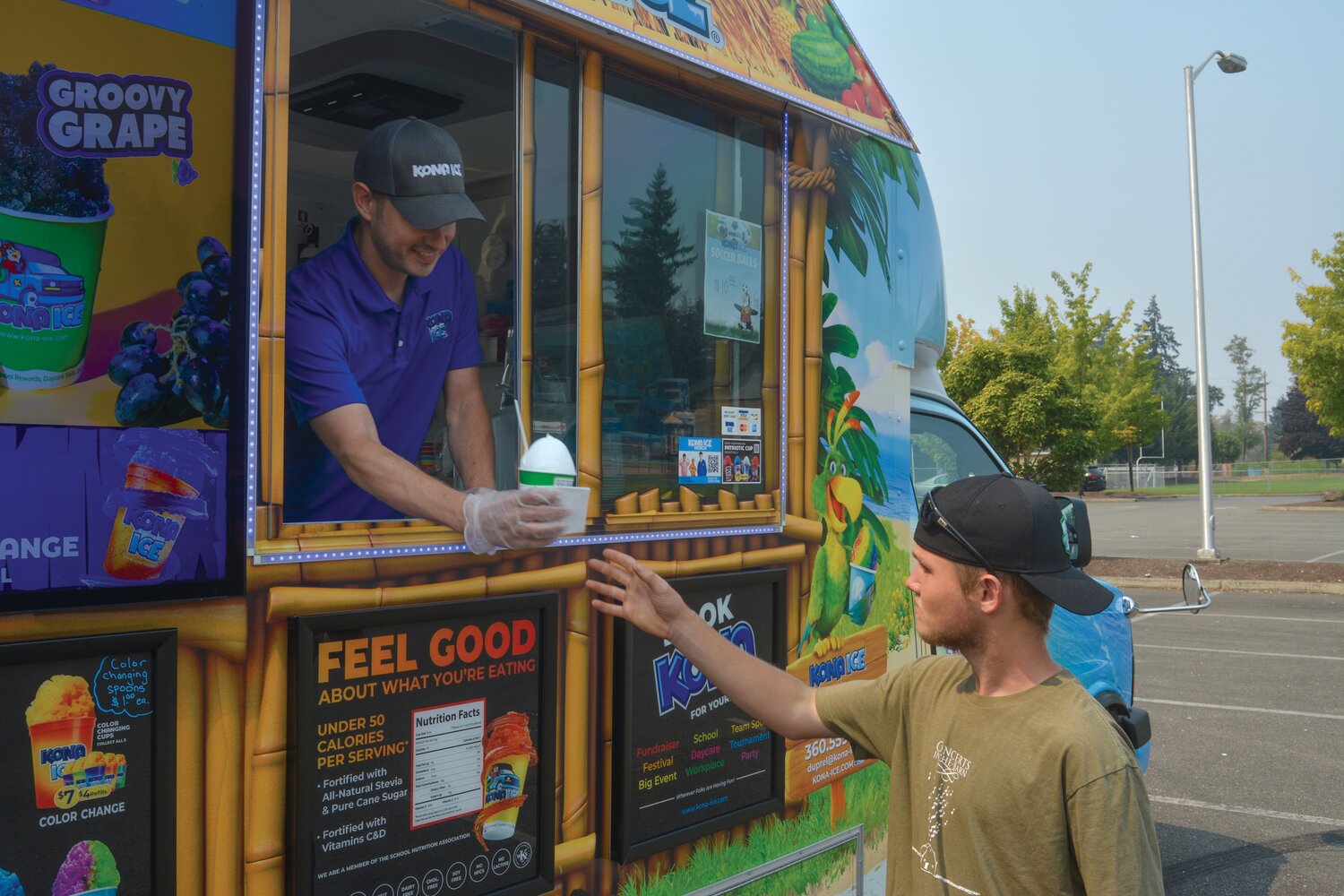 Matt Duprel hands a customer shaved ice at Longmire Community Park on Aug. 20.