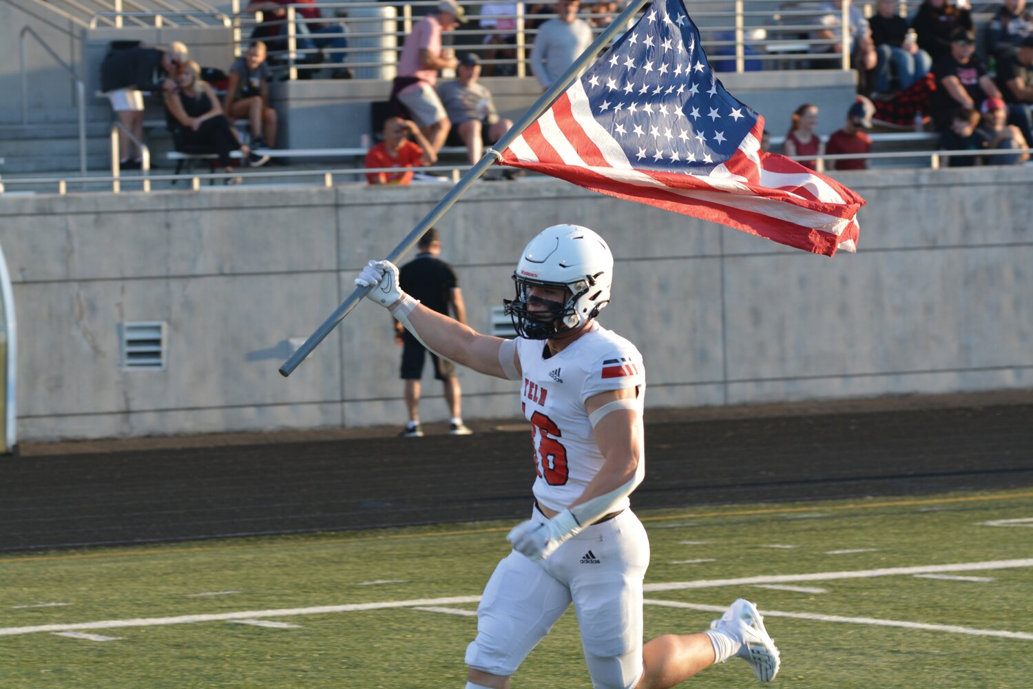 Junior linebacker Nathan Ford carries the American flag onto the field pre-game on Sept. 1 against Camas High School.