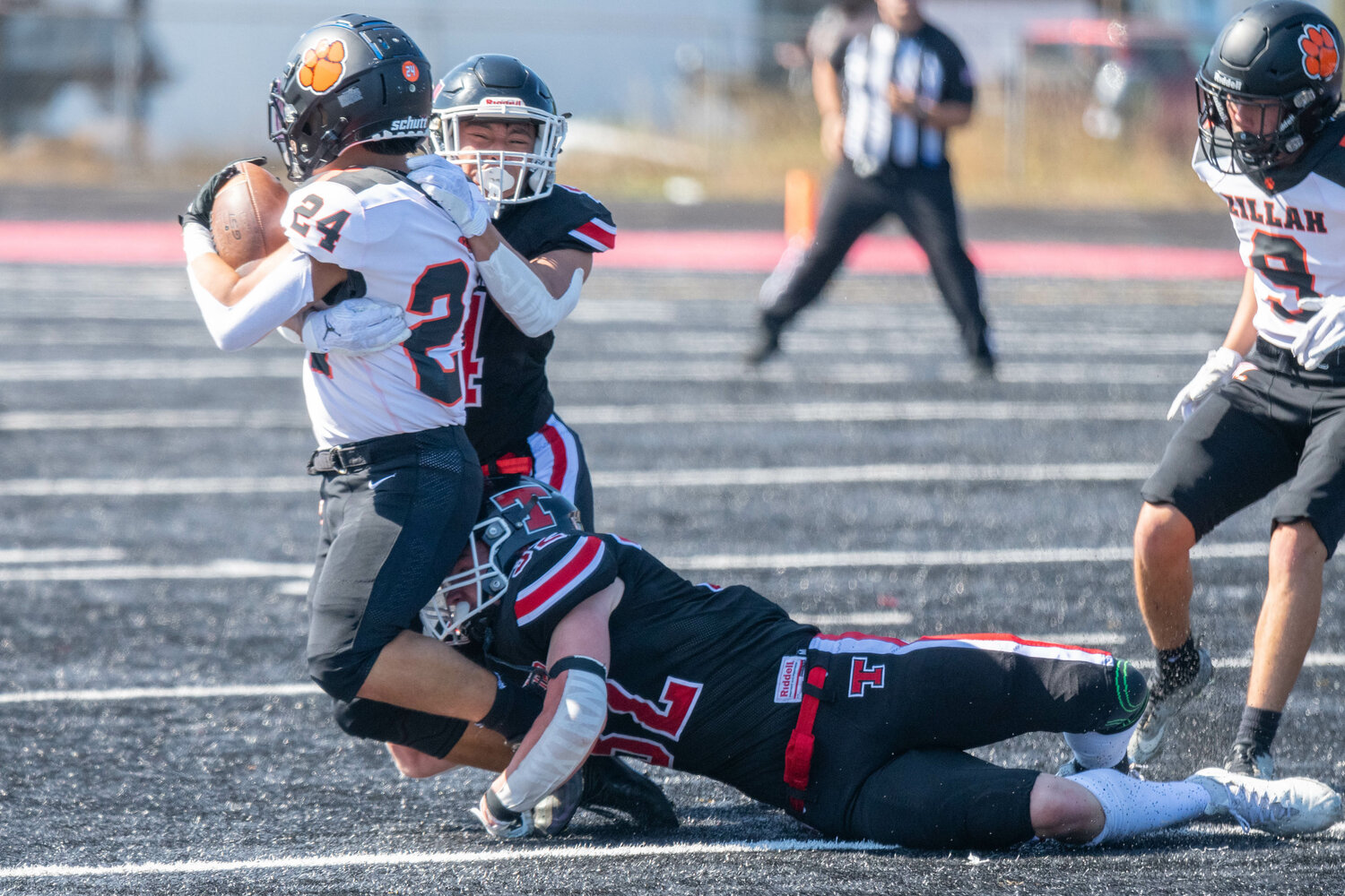 Mikey Vassar (#2) and Lucas Watterson (4) combine to take down Zillah's Yizzy Sandoval during the first half of Tenino's 34-32 loss to Zillah on Sept. 9.