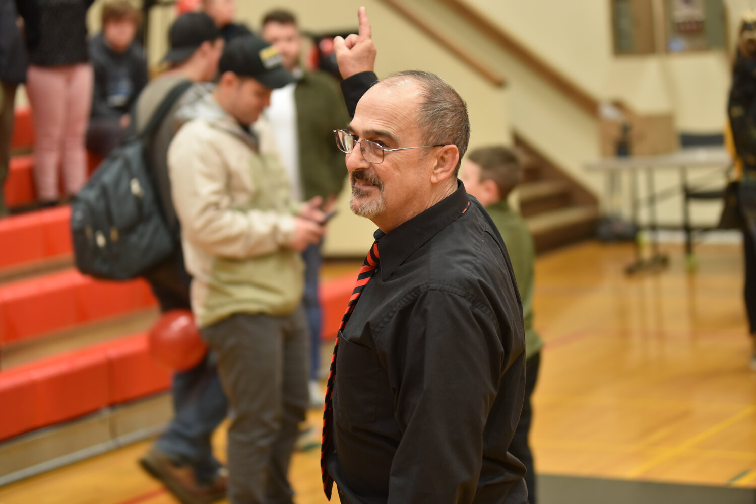 Yelm's head wrestling coach Gaylord Strand smiles and points to the scoreboard on Jan. 23 after the Tornados defeated the Bison, 37-36, in the "Bad to the Bone" dual.