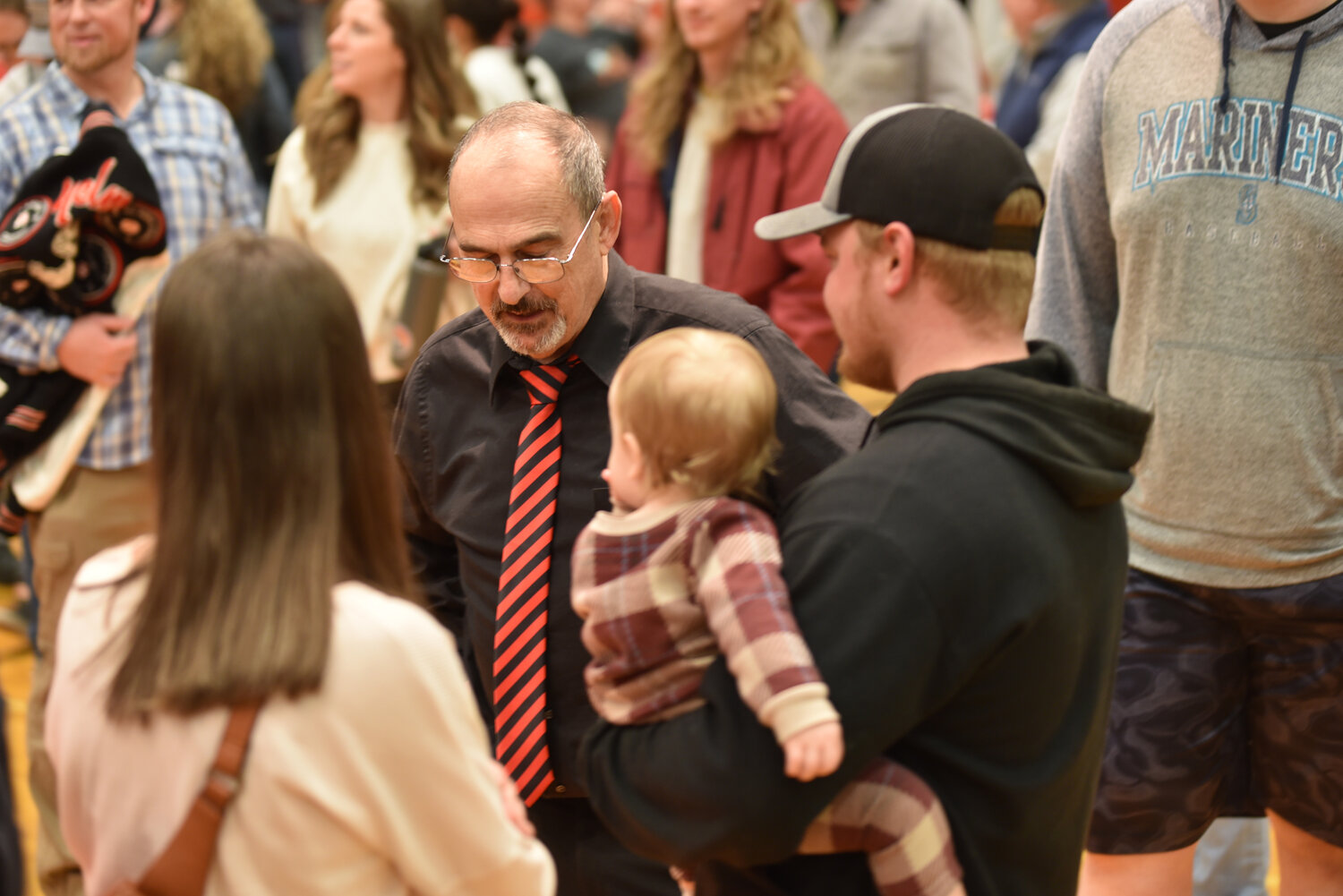 Yelm's head wrestling coach Gaylord Strand talks with former Tornados wrestler Cody Frye and his son on Jan. 23 following the coaches final home dual.