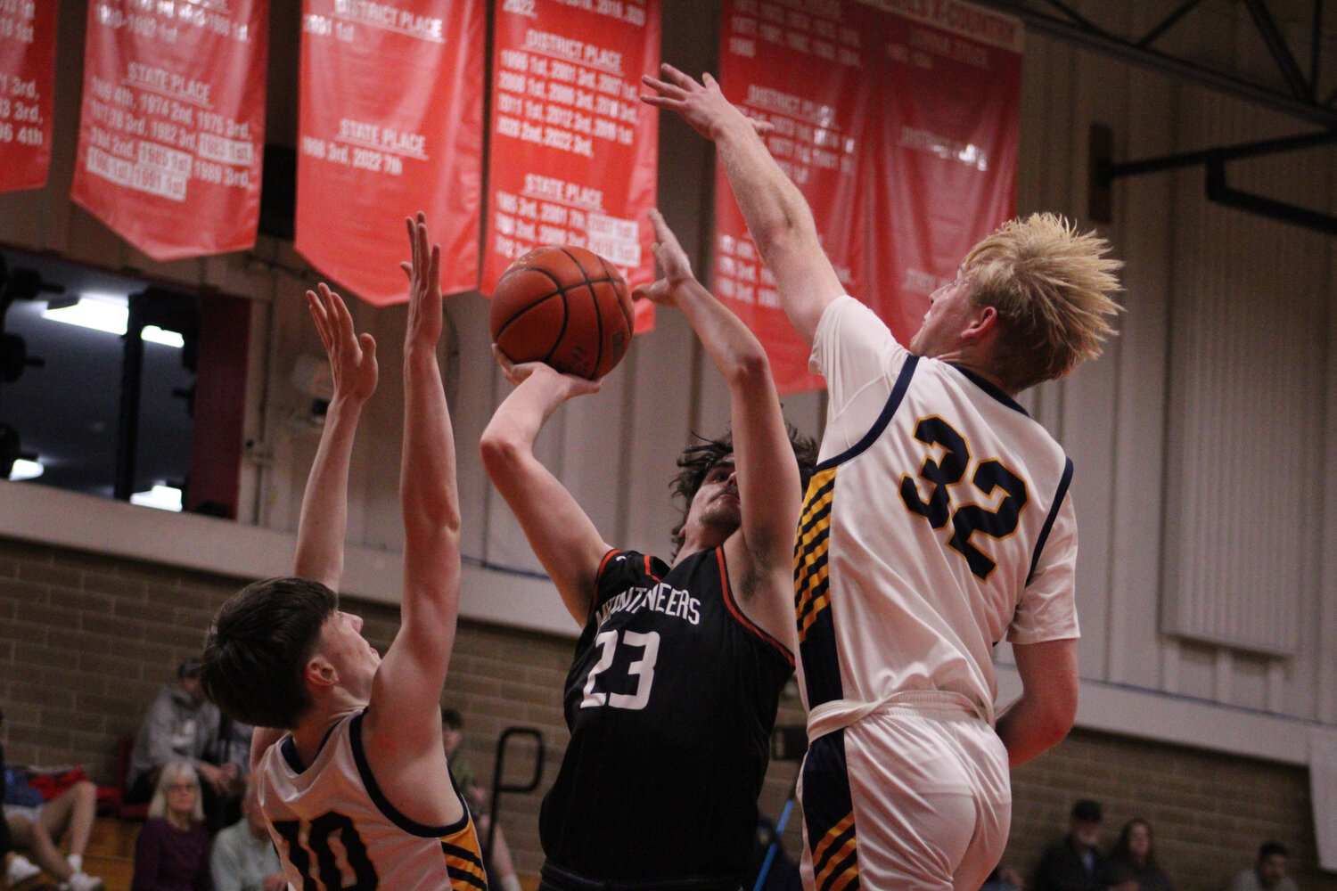 Jared Sprouffske endures contact from two Adna defenders to lay in a shot on Feb. 9.